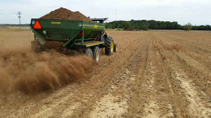 Applying chicken litter to field using mechanical spreader