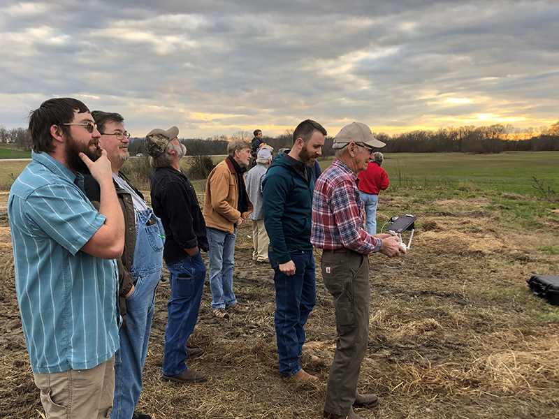 Group of farmers watching drone.